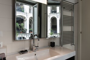 A modern bathroom with a large mirror, a white sink, and a towel rack.