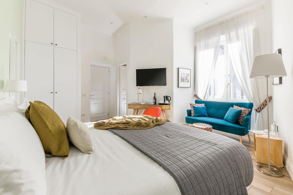 Une chambre avec un lit, un bureau, une chaise, un canapé et un téléviseur.