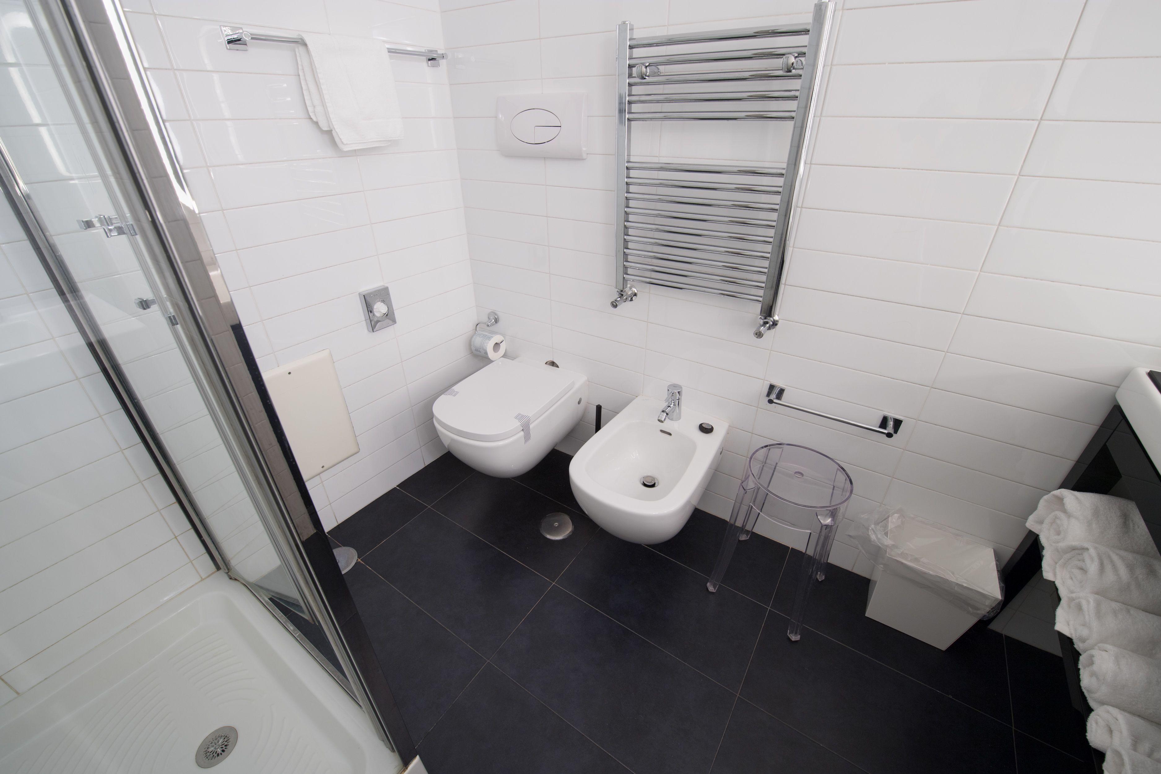 Un bagno moderno con cabina doccia in vetro, un bidet, un water e un porta asciugamani.