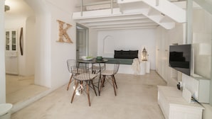 Un intérieur moderne comprenant un coin repas, un escalier et un téléviseur.