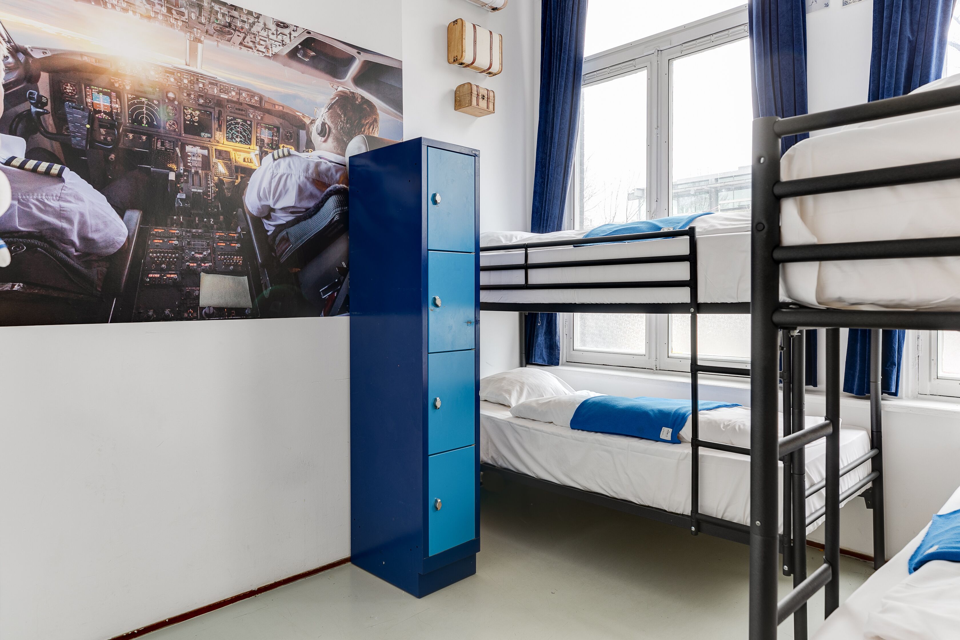 A bunk bed room with a blue wardrobe and a poster of pilots on the wall.