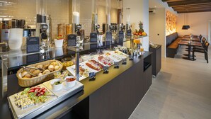 A buffet area with various food items and a seating area with a long table and chairs. - VitalBoutique Hotel Zurzacherhof (Bad Zurzach)