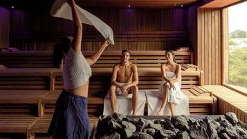 Una sauna con bancos de madera, una pileta de piedra y un ventanal grande.
