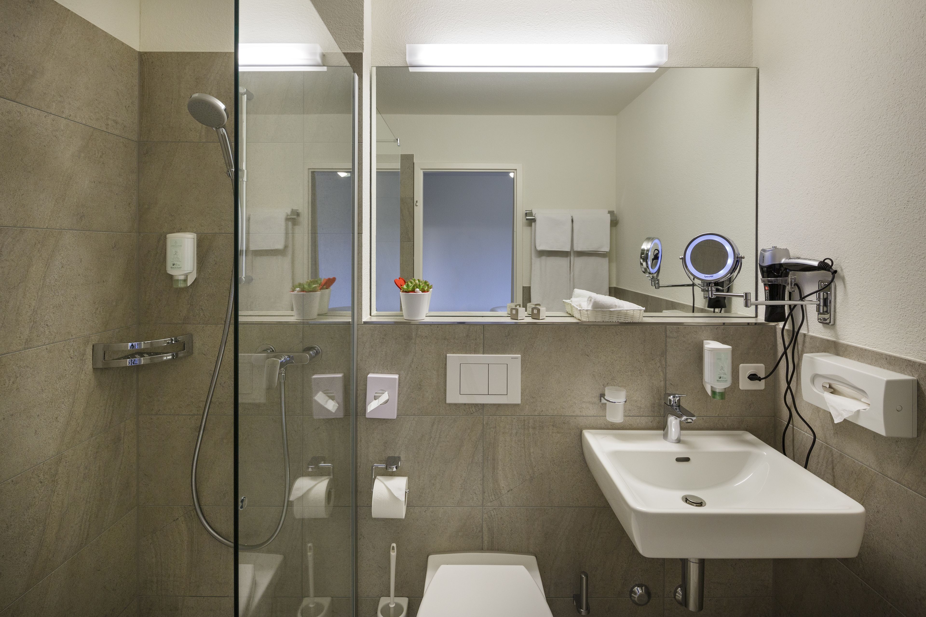 Un baño moderno con cabina de ducha de vidrio, un lavamanos y un espejo.