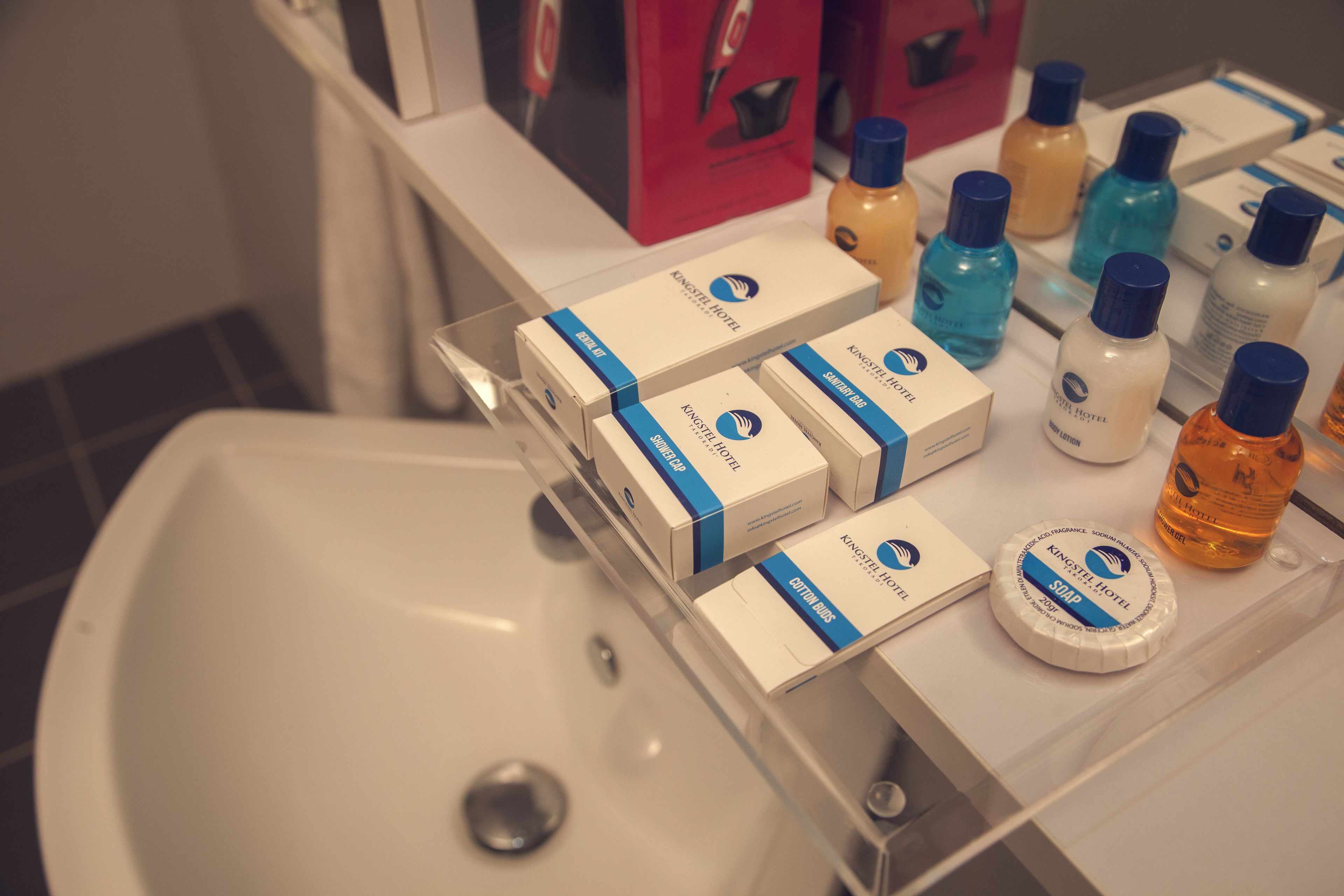 Una encimera de baño con diversos artículos de aseo y un lavabo blanco.