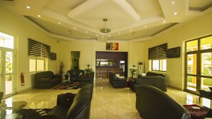 A spacious lobby with leather sofas, a bar area, and large windows. - Kingstel Hotel (Sekondi-Takoradi)