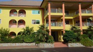 A two-story building with a yellow facade, multiple balconies, and a central entrance. - Kingstel Hotel (Sekondi-Takoradi)