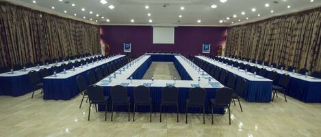 A conference room with a long table, chairs, and a projector screen.