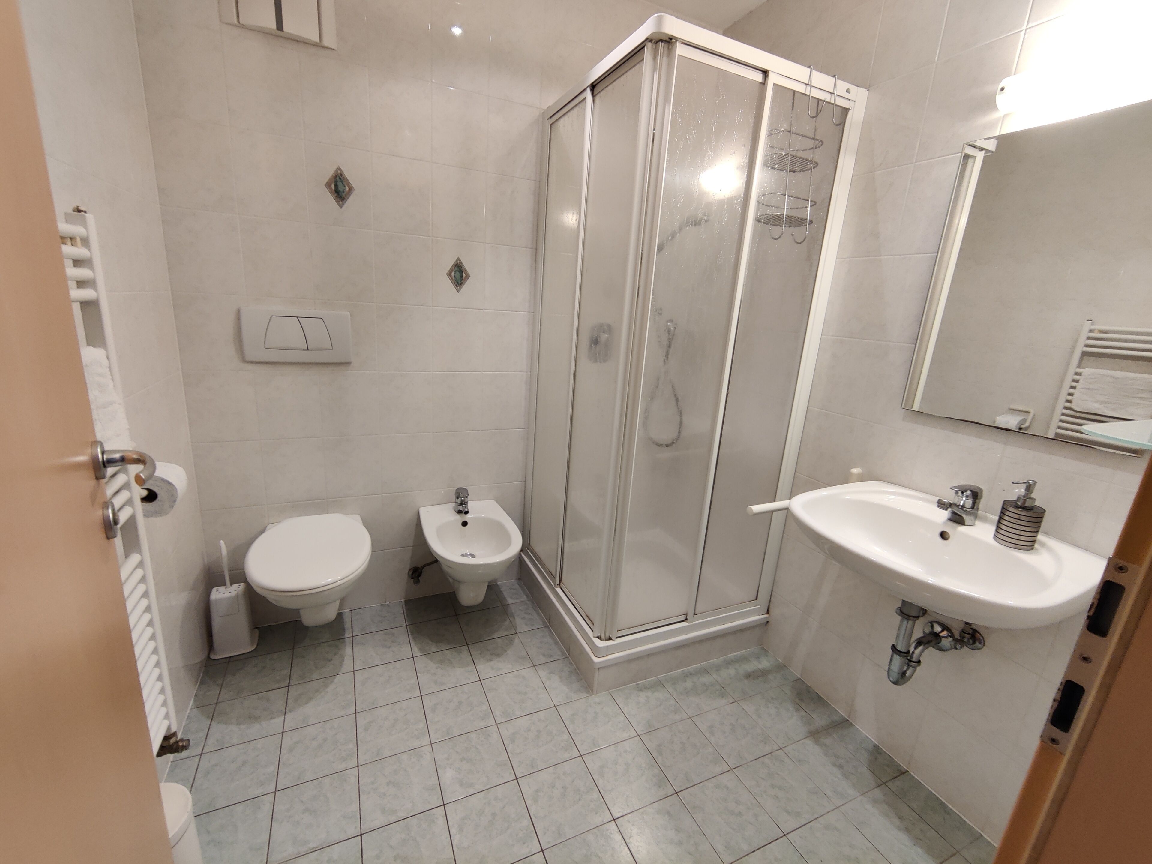 A modern bathroom with a shower, toilet, bidet, and sink.