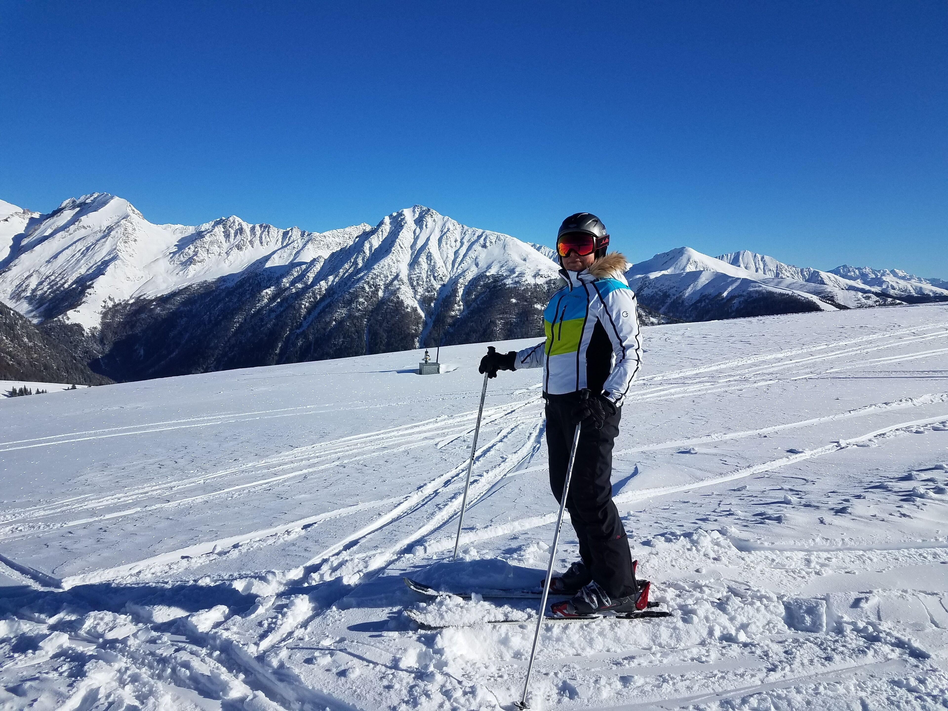 Una persona esquiant-se en una pendent nevada amb un paisatge de muntanyes al fons.