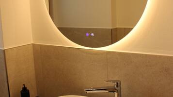 A modern bathroom with a round mirror, a white sink, and a towel on the counter.