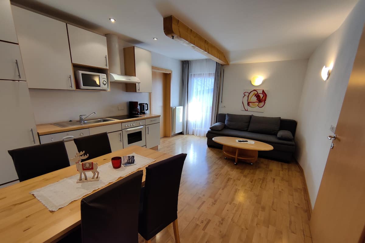 Una cocina moderna con microondas, estufa y cafetera. Hay una mesa de comedor con sillas y un sofá en la sala.