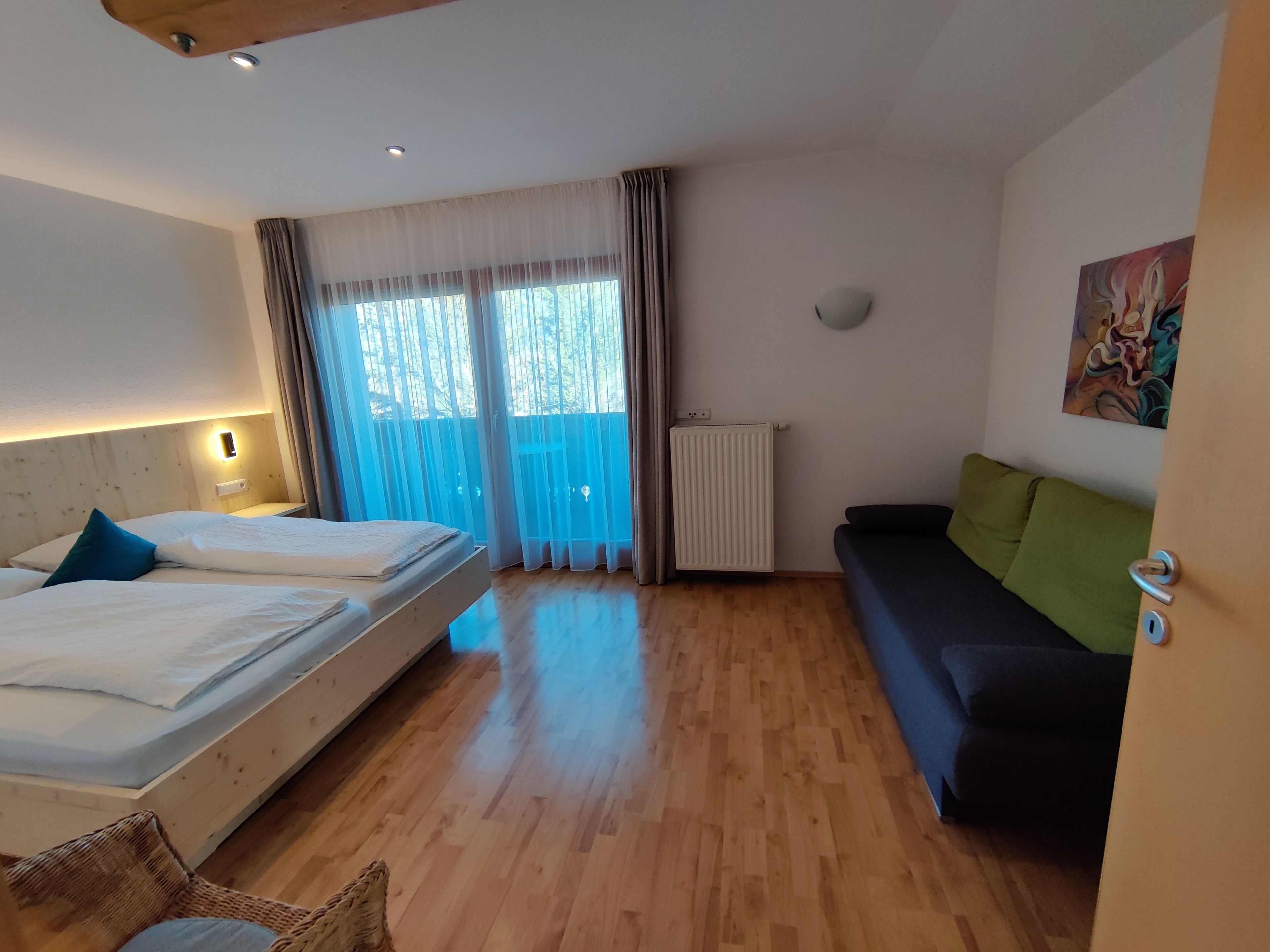 Ein Hotelzimmer mit Bett, einer Couch, einem Heizkörper und einem Bild an der Wand.