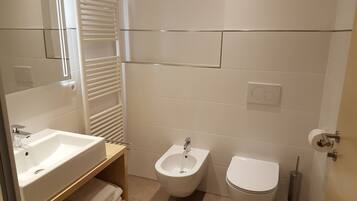 Un baño moderno con lavabo, bidé, inodoro y perchero para toallas.