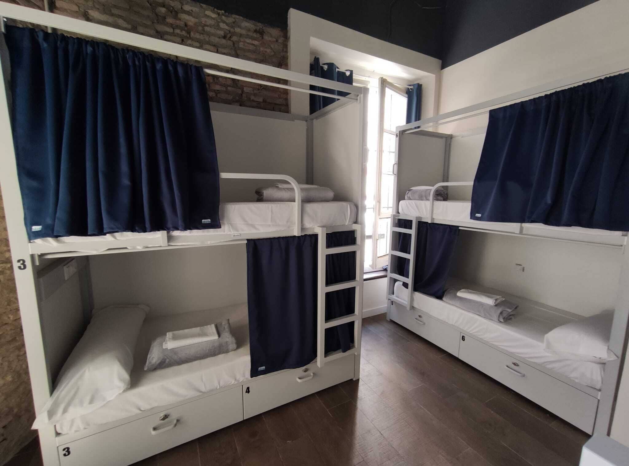 Un dormitorio con literas, una ventana con cortinas y una pared de ladrillo.