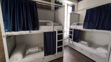 Un dormitorio con literas, una ventana con cortinas y una pared de ladrillo.