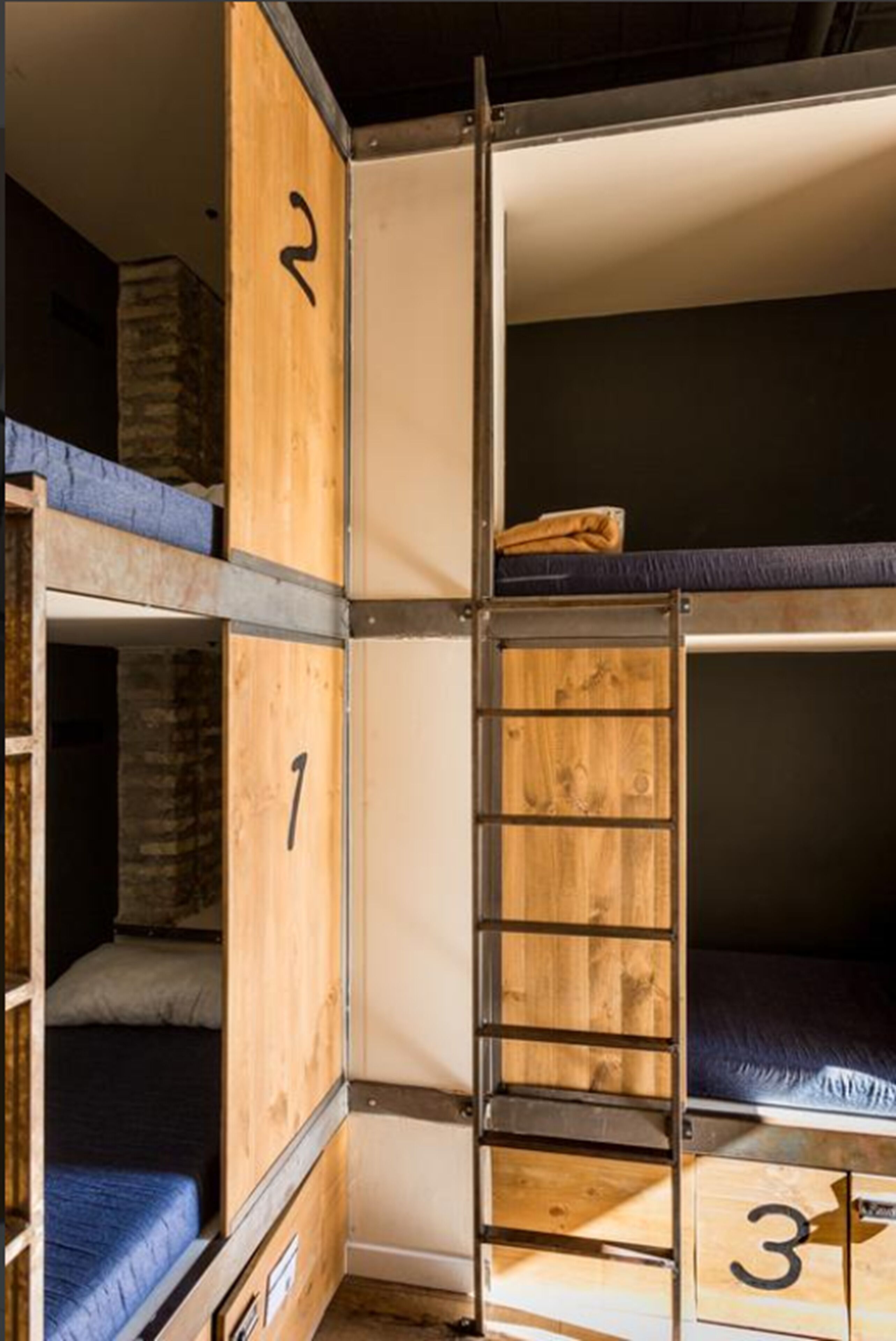 A bunk bed room with wooden walls and metal railings.