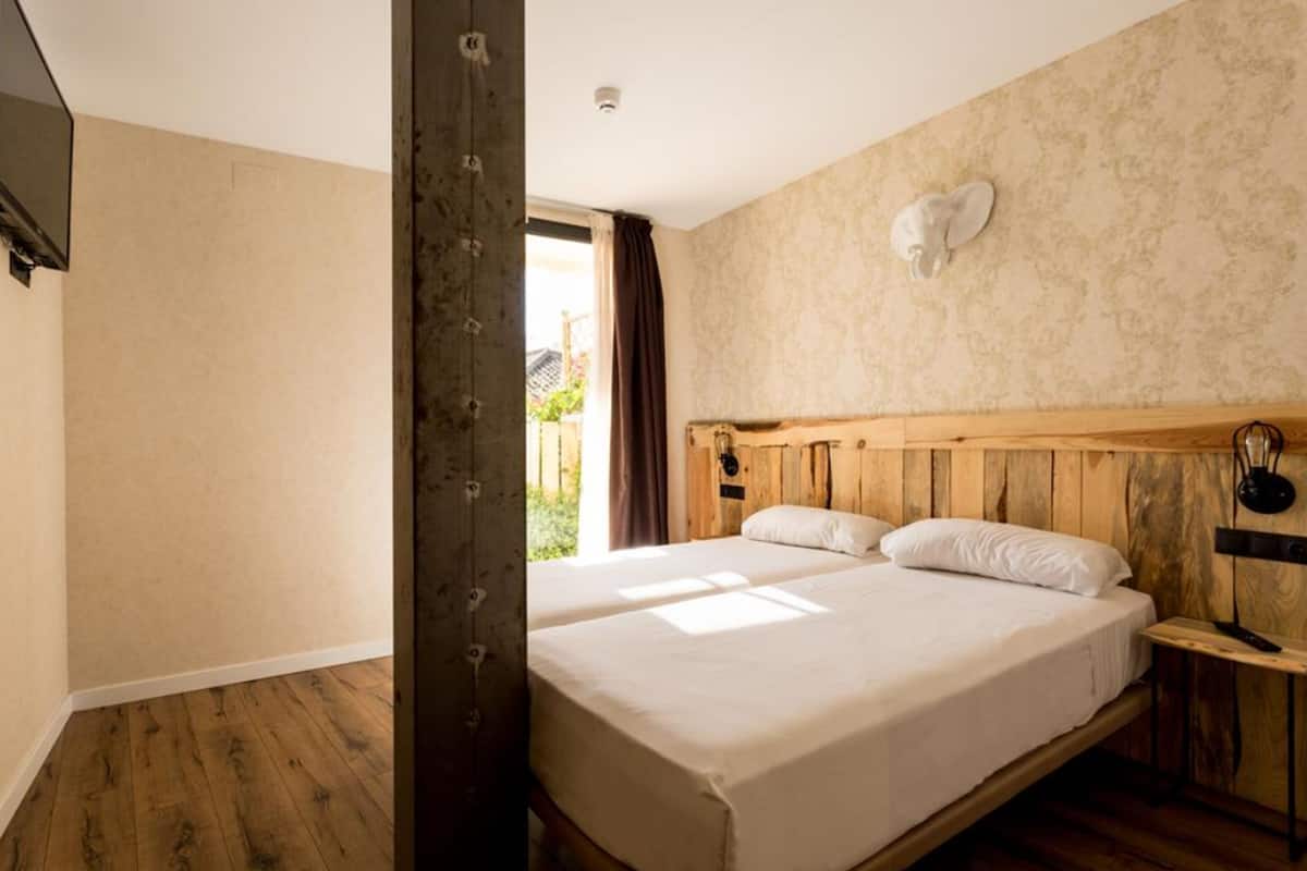 Un dormitorio con dos camas, cabeceros de madera y una mesita de noche.
