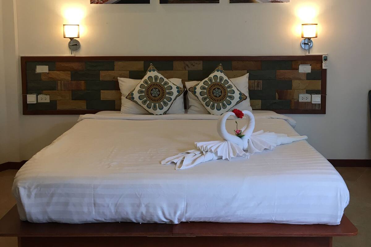 A hotel room with a large bed, two wall-mounted picture frames, and two wall-mounted lamps.
