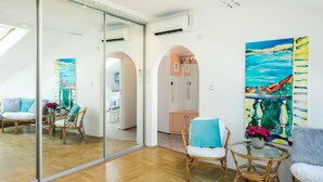A modern living room with a glass partition, wicker furniture, and a large painting on the wall. - All In Apartments (Kraków)