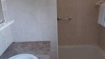 A bathroom with a sink, shower, and tiled walls.
