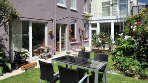 A two-story building with a patio area featuring a table and chairs. - Hotel Manitoba (Blankenberge)