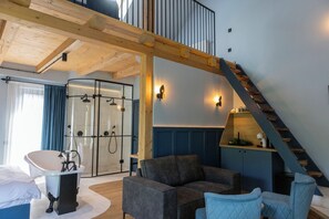 Un interior moderno con techo de madera, cabina de ducha de vidrio, sofá y escalera.