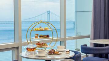 Une table avec un service à thé et des pâtisseries, donnant sur un pont.