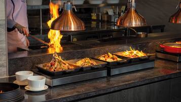 Un buffet proposant divers plats, un chef cuisinier et un foyer.