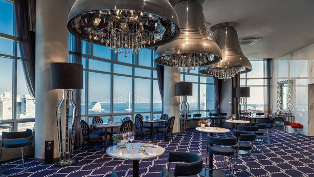 A modern hotel lobby with large windows, a patterned carpet, and multiple dining tables and chairs. - Kent Hotel Gwangalli by Kensington (Busan)