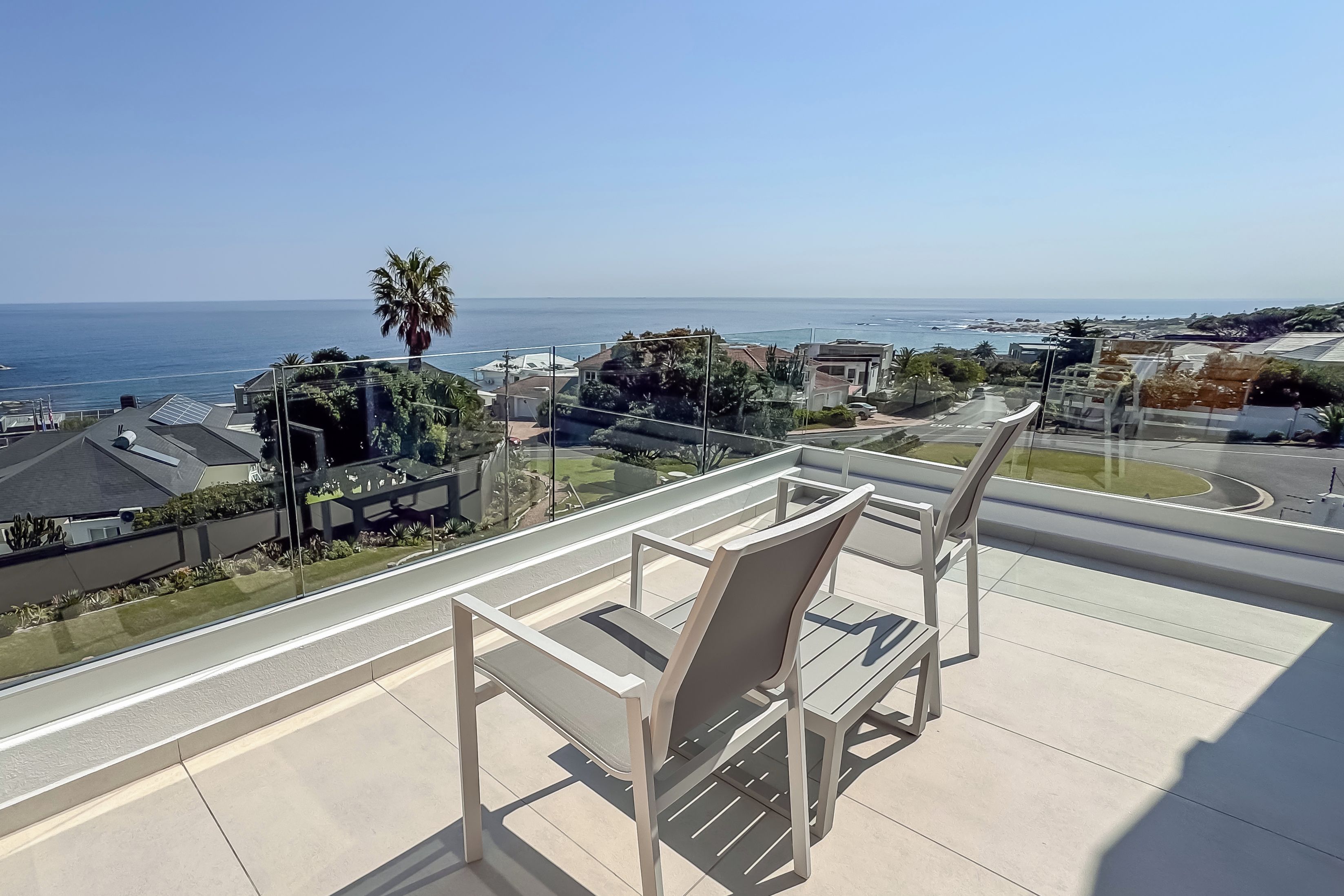 A balcony with a view of the ocean and a residential area.