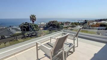 A balcony with a view of the ocean and a residential area.
