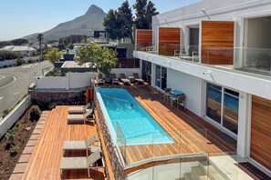 A modern pool area with a clear view of the ocean and a mountain in the background. - Finchley Guest House (Cape Town)