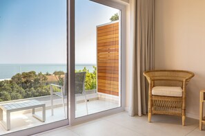 A balcony with a view of the sea, a wicker chair, and a white table. - Finchley Guest House (Cape Town)
