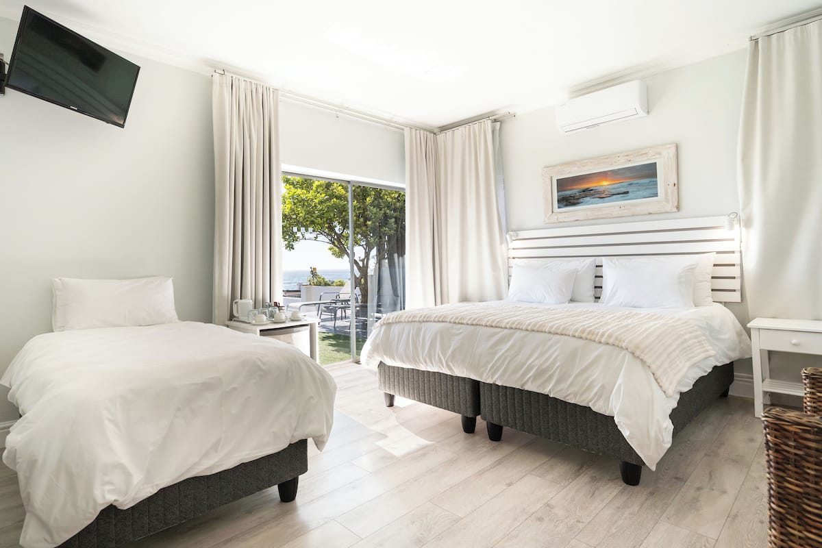 Habitación de hotel con dos camas, televisión, un cuadro y vista al mar.