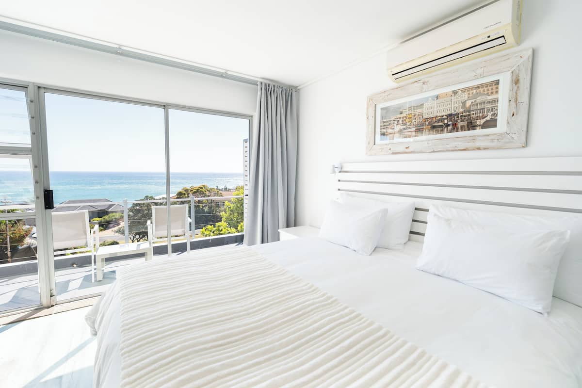 Un dormitorio con una cama grande, vistas al océano y un cuadro en la pared.