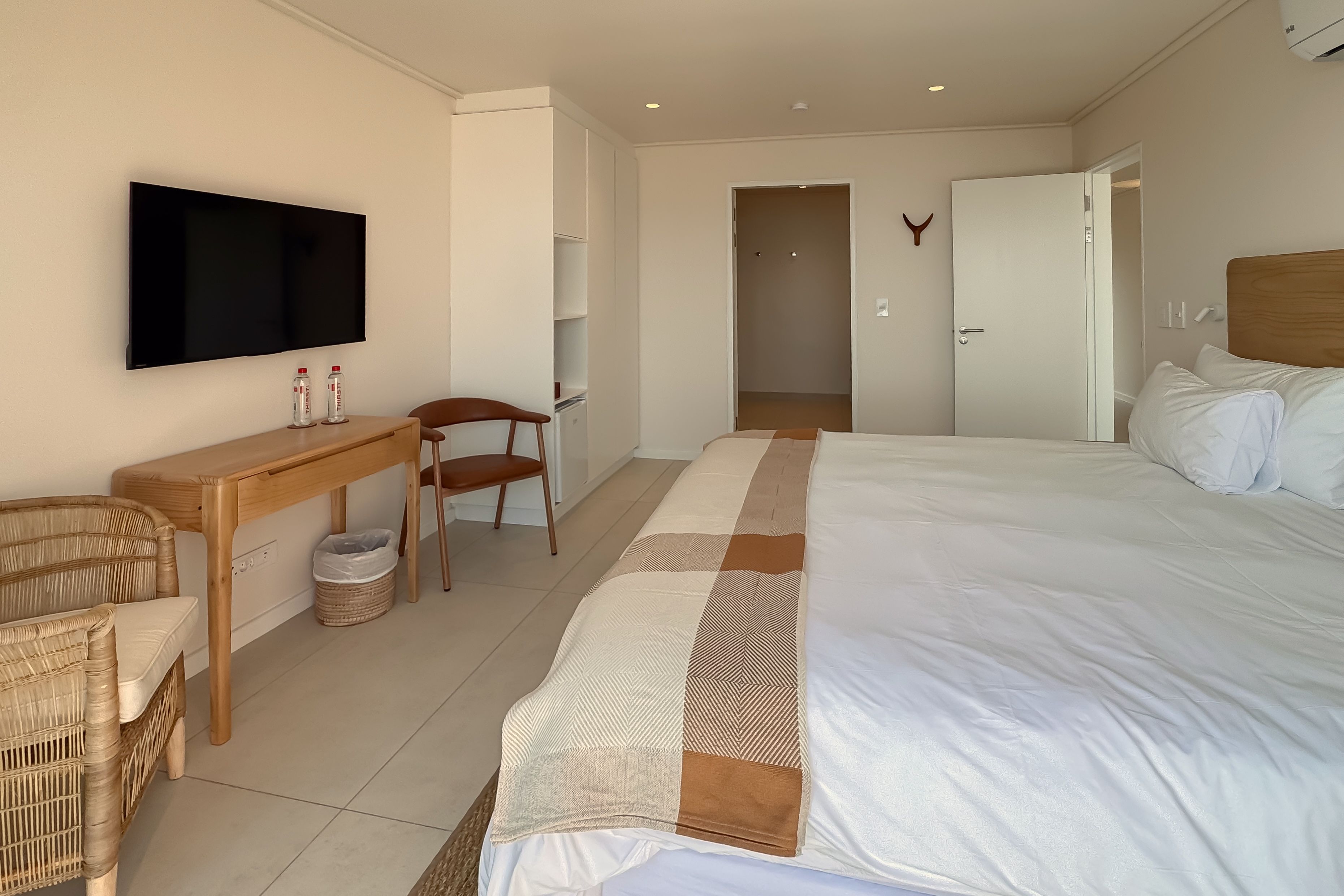 A hotel room with a bed, a desk, a chair, a television, and a wardrobe.