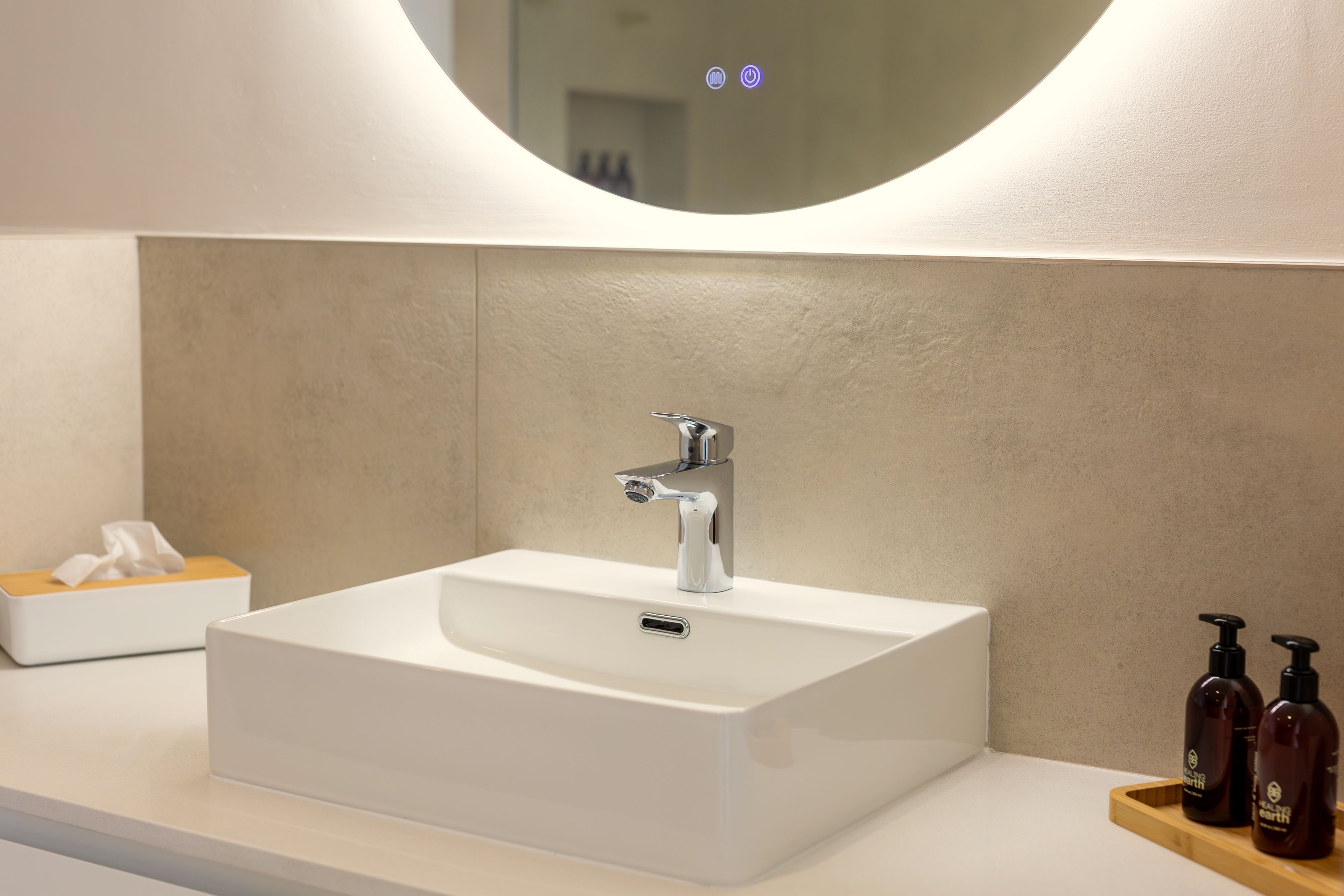 A bathroom with a white sink, a mirror, and a tissue box.