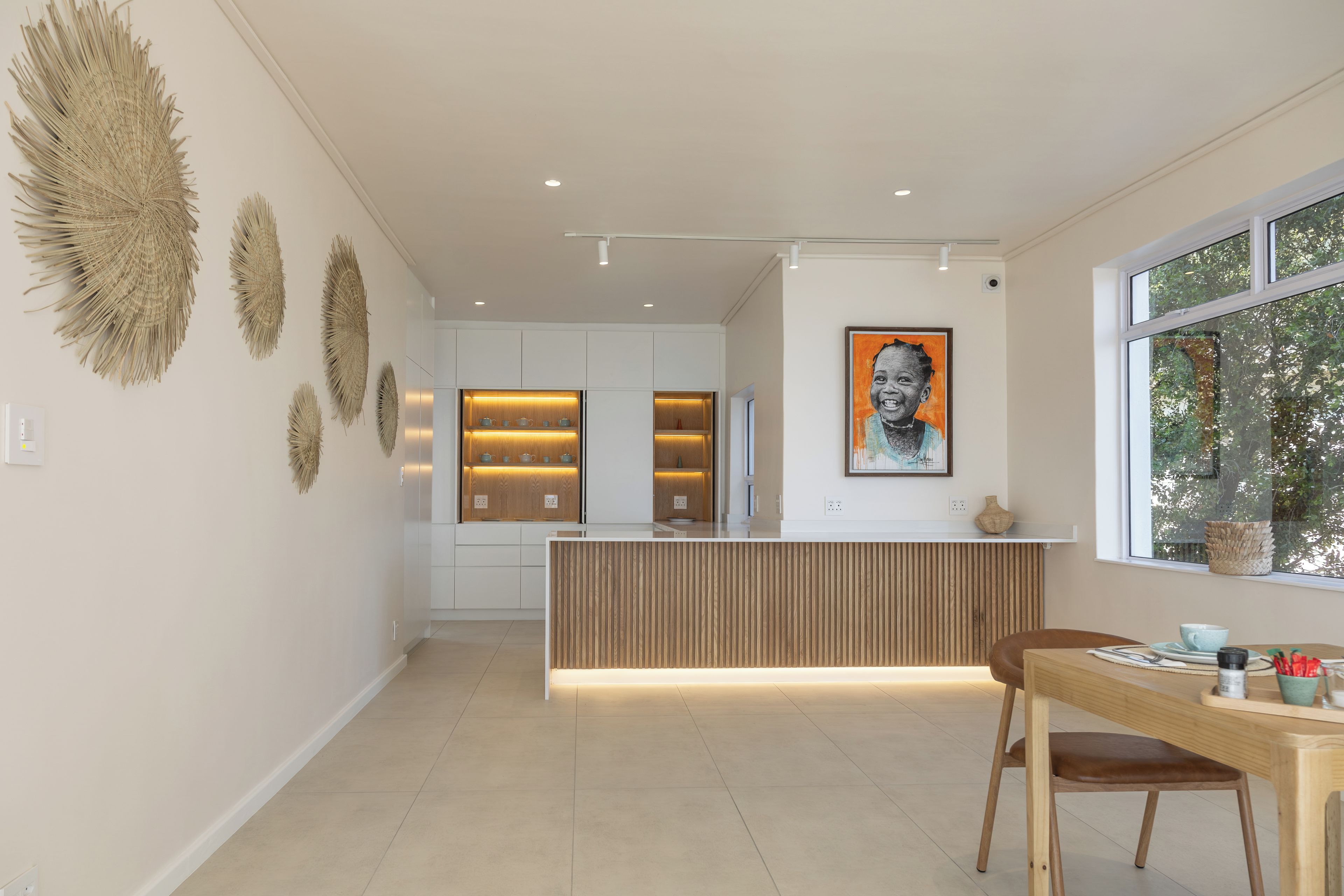 A modern kitchen with a central island, pendant lighting, and decorative wall art.