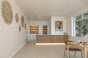 A modern kitchen with a central island, pendant lighting, and decorative wall art. - Finchley Guest House (Cape Town)