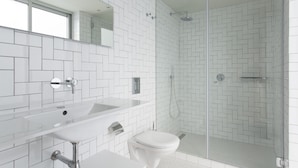 Une salle de bain moderne avec un lavabo blanc, des toilettes et une douche à parois de verre.