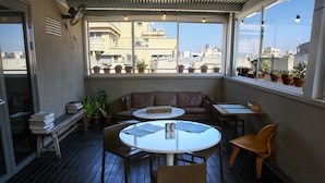 Un espace patio accueillant avec une table ronde, deux chaises, un canapé et plusieurs plantes en pot.