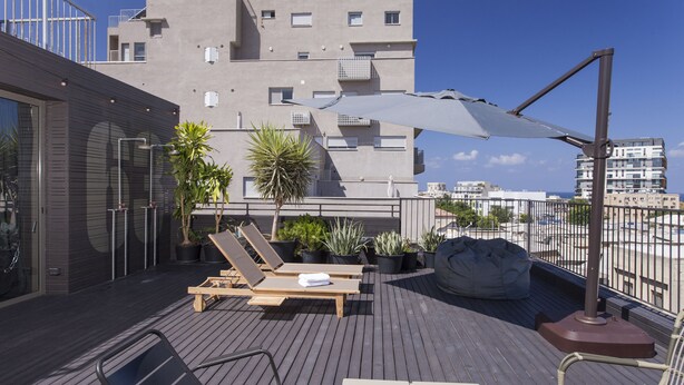 Une terrasse sur le toit, aménagée avec des fauteuils en bois, une table et des plantes en pot.