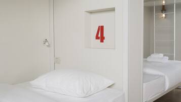 Une chambre d’hôtel avec un lit, un numéro « 4 » fixé au mur et une salle de bain équipée d’un porte-serviettes.