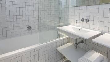 Un baño moderno con ducha envuelta en cristal, un lavabo blanco y un mueble de tocador.