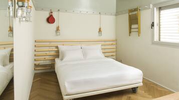 Een slaapkamer met een bed op wielen, een houten hoofdbord en een raam met zonwering.