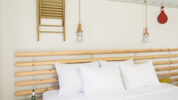 A bed with white bedding, a wooden headboard, and a bedside table with a bottle and glasses.
