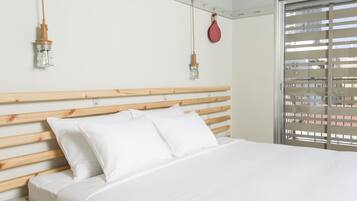 Una cama bien hecha con sábanas blancas, un cabecero de madera y dos lámparas colgantes.