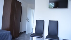 A hotel room with a wardrobe, two black chairs, a flat-screen TV, and a bed with a grey bedspread. - Zwei Raben Pension (Mainz)