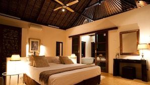 A spacious bedroom with a large bed, bedside lamps, a ceiling fan, and a wooden floor. - Chuiba Bay Lodge (Pemba)